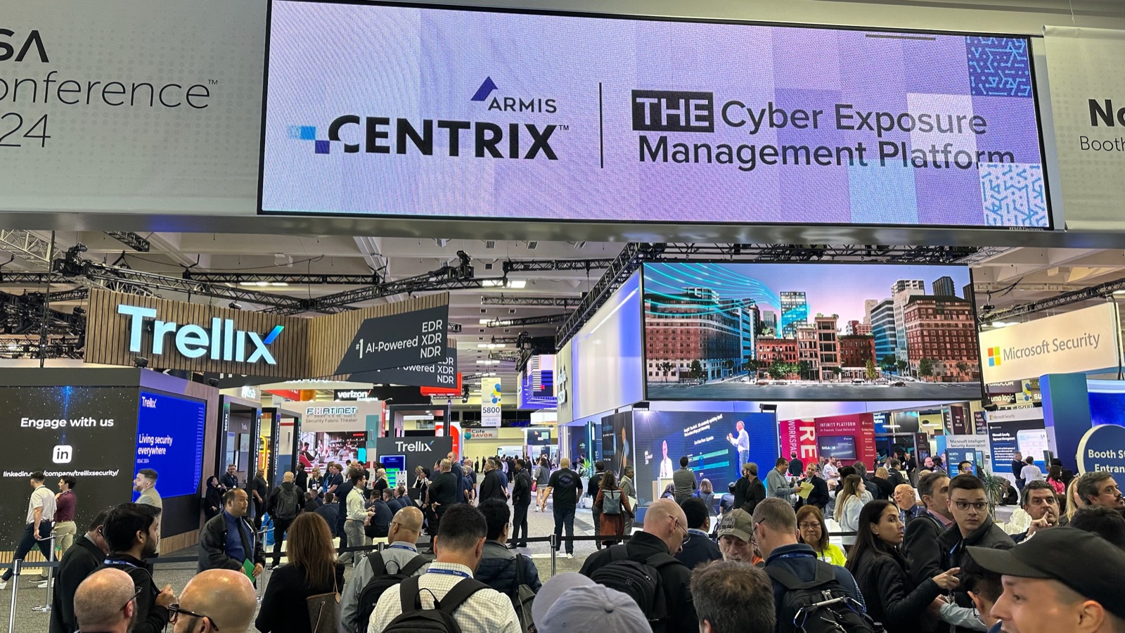 Piso del expo de RSA Conference 2024, multitud alrededor de stands con branding y pantallas grandes arriba.