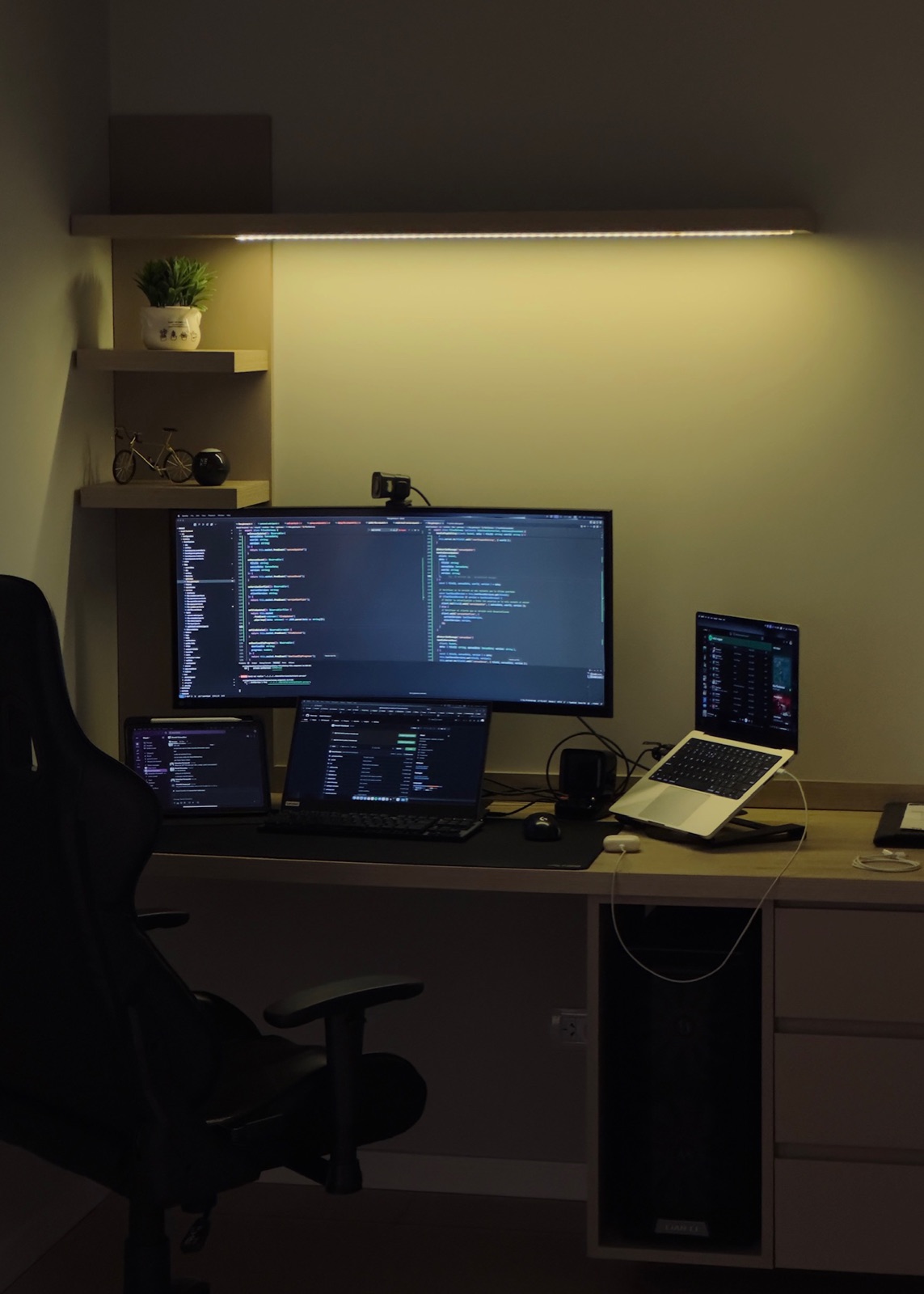 Same desk during work hours, code on the ultrawide, second laptop screen with a build running, iPad in the back showing notes.
